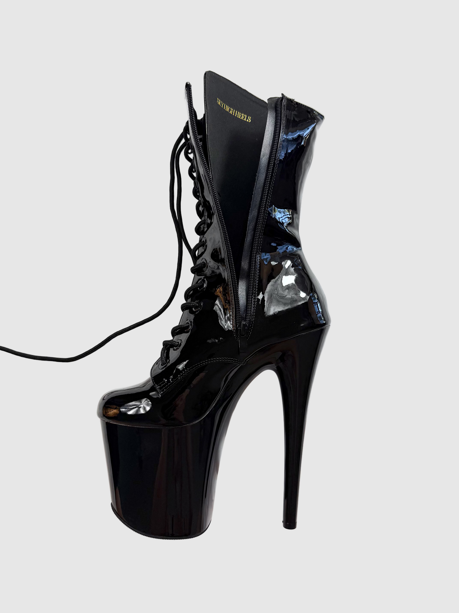 Black high-heeled platform boot on a white surface